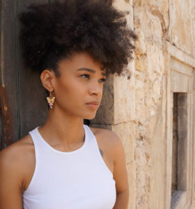 Fille brune qui porte des boucles d'oreilles en forme de triangle