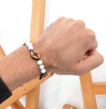 main portant un bracelets avec des perles blanches