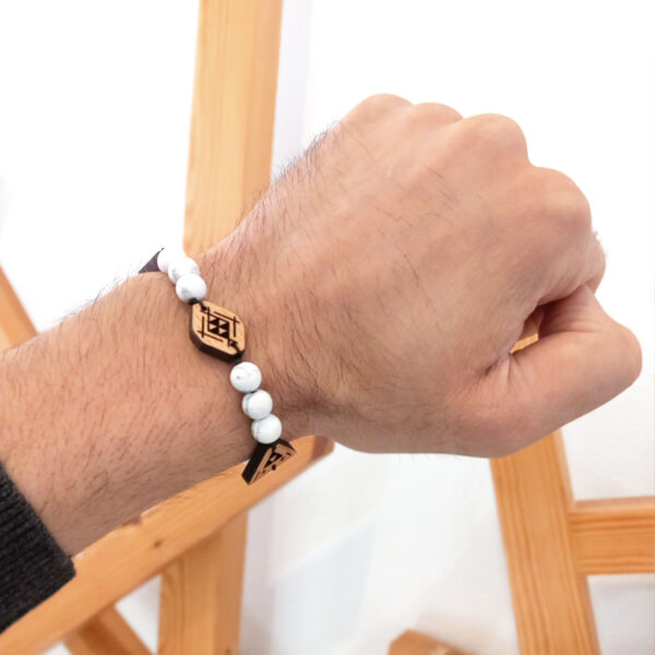 main portant un bracelets avec des perles blanches