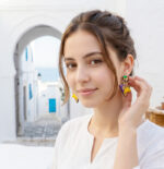 Fille brune avec boucles d'oreilles colorées dans un décors architectural et coloré